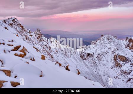 Chaîne de falaises rocheuses couvertes d'une couverture blanche de neige après une chute de neige récente sur fond de nombreuses vallées à rayons du soleil Banque D'Images