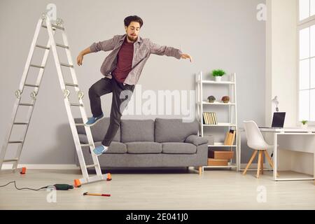 Le jeune homme malchanceux a glissé de l'échelle tout en faisant à la maison réparations et rénovation de la maison Banque D'Images