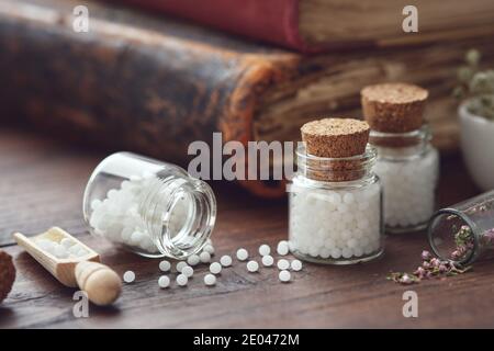 Flacons de globules homéopathiques et de vieux livres. Concept de médecine d'homéopathie. Banque D'Images