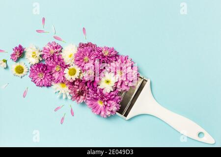 Composition des fleurs. Mise en page créative composée de fleurs roses et blanches et d'un pinceau sur fond bleu pastel. Flat lay, vue de dessus, espace de copie. Banque D'Images
