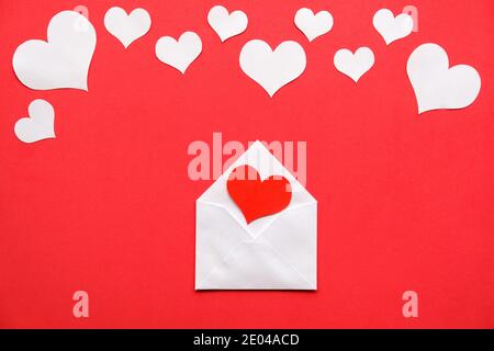 Thème de la Saint-Valentin. Enveloppe blanche avec coeur rouge à l'intérieur, coeur blanc sur fond rouge. Banque D'Images