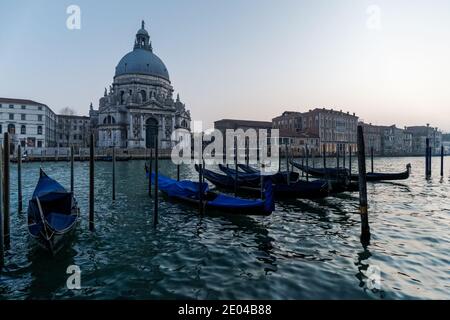 Gondole vénitienne au coucher du soleil, gondoles amarrées à Venise avec la basilique Santa Maria della Salute en arrière-plan, en Italie