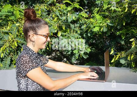 Jeune femme travaillant à distance à l'extérieur. Vue frontale. Banque D'Images