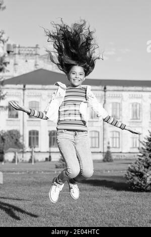 un vrai bonheur. donnez vie à votre enfant. joyeux saut à la hauteur. sens de la liberté. bonheur d'enfance. petite fille avec des cheveux bouclés en plein air. vacances de printemps enfin. enfant célébrant le succès. Banque D'Images