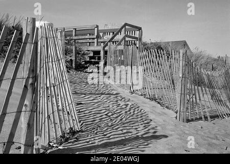 Des clôtures et des ombres en bois et en fil de fer sillonnent les deux côtés d'un chemin dans le sable menant aux escaliers d'un patio à Salisbury Beach, Massa Banque D'Images