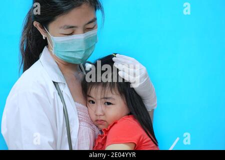 Une jolie jeune fille asiatique se sentant effrayée et nerveuse avant se faire vacciner est réconforté par son médecin qui l'est port d'un masque chirurgical avec un coup Banque D'Images