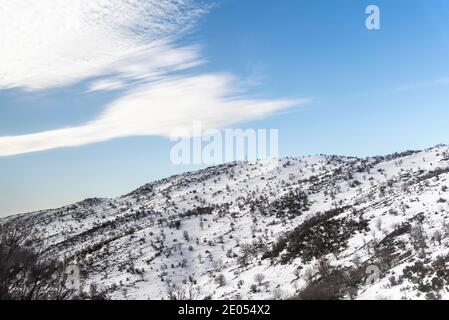 Une montagne couverte de neige peu profonde. Les buissons sortent de la neige. Ciel bleu ciel nuageux. Chalet en rondins. Pavillon en bois. Plateau du Golan. Mont Hermon. Photo de haute qualité Banque D'Images