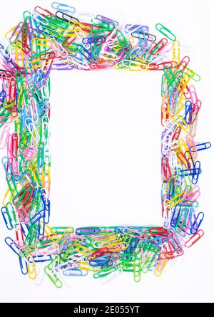 Cadre composé de trombones colorés sur fond blanc, vue du dessus avec espace pour le texte ou la créativité. Banque D'Images