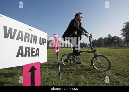 Un jeune homme participant portant un costume sur une bicyclette pliante Brompton aux Championnats du monde Brompton, qui se tiennent au Palais de Blenheim, Royaume-Uni . Banque D'Images