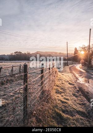 Un champ de brume gelé au lever du soleil. Les couches de brume se déposent sur le sol inférieur à travers une vue classique de la campagne britannique au lever du soleil en hiver. Banque D'Images