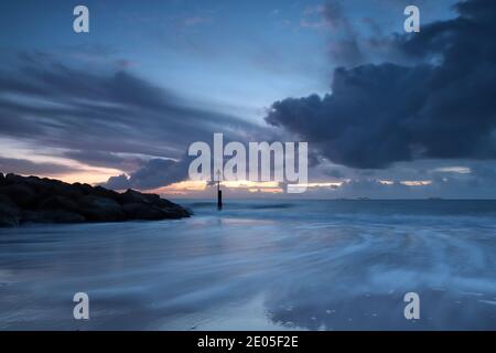 Les vagues se précipitent vers la caméra sur la plage de Bournemouth dans une ambiance froide et discrète de l'heure bleue. Le ciel est plein de nuages lourds avec la promesse de la pluie. Banque D'Images