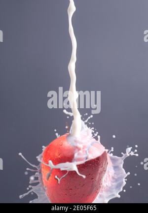 Éclaboussures de lait avec pomme sur fond gris. Banque D'Images