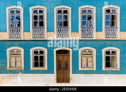 Une vue frontale d'une façade de maison couverte en azulejo carreaux avec fenêtres cassées et porte en bois Banque D'Images