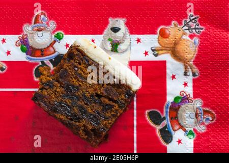 Tranche de gâteau de Noël aux fruits glacé M&S mise en place Serviette de plage rouge de Noël - Noël festif au Royaume-Uni Banque D'Images