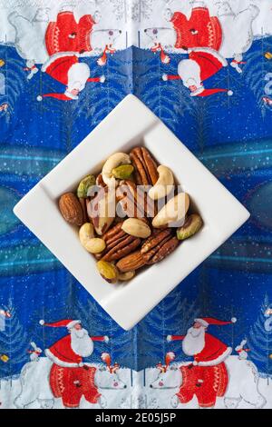 Bol de noix, noix de cajou, amandes, braises, pacanes et pistaches, noix non salées sur la serviette de Noël en serviette - Noël festif Banque D'Images
