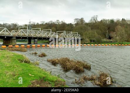 Perche de sécurité orange étirée sur une rivière en face de un pont ferroviaire Banque D'Images