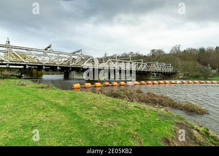 Perche de sécurité orange étirée sur une rivière en face de un pont ferroviaire Banque D'Images