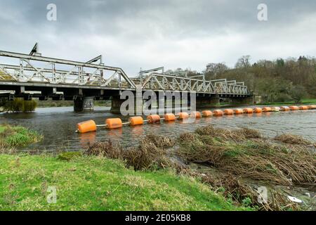 Perche de sécurité orange étirée sur une rivière en face de un pont ferroviaire Banque D'Images