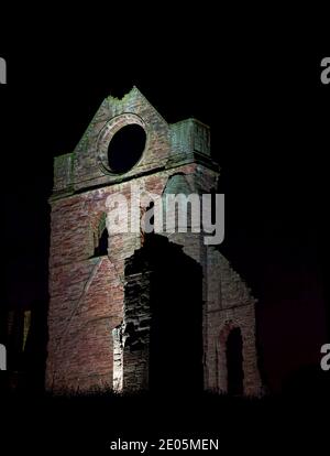 La tour transept sud de l'abbaye d'Arbroath avec sa fenêtre ronde distinctive, éclairée par des projecteurs dans une soirée froide de décembre. Banque D'Images