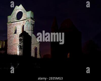 La tour sud du transept des ruines de l'abbaye d'Arbroath avec sa fenêtre ronde distinctive, éclairée par des projecteurs lors d'une soirée de Noël froide et claire. Banque D'Images