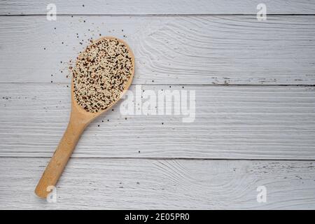 Mélange de quinoa cru dans une cuillère en bois sur une table de cuisine en bois blanc. Vue de dessus. Aliments sains et diététiques super. Aliments végétaliens Banque D'Images