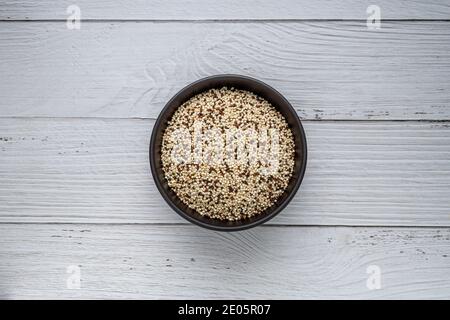 Mélange de quinoa cru dans un bol sur une table de cuisine en bois blanc. Vue de dessus. Aliments sains et diététiques super. Aliments végétaliens Banque D'Images