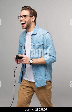 jeune homme en jean décontracté chemise tenant joystick ou manette de jeu jouer Banque D'Images