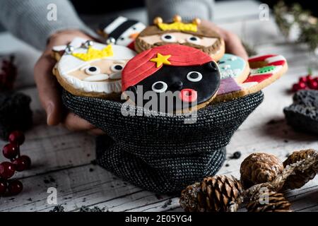 gros plan d'un jeune homme caucasien avec sac tricoté dans sa main avec une pile de biscuits de noël avec différentes formes et couleurs, comme les trois wis Banque D'Images