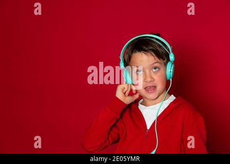 jeune garçon cool avec casque turquoise et chandail rouge est poser Banque D'Images