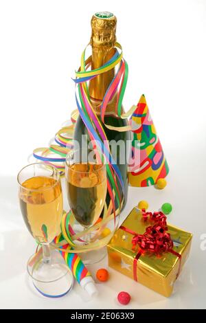 Concept de fête du nouvel an avec bouteille et verre de champagne, ruban en papier, confetti, chapeaux de fête et cadeaux. Photo sur fond blanc. Banque D'Images