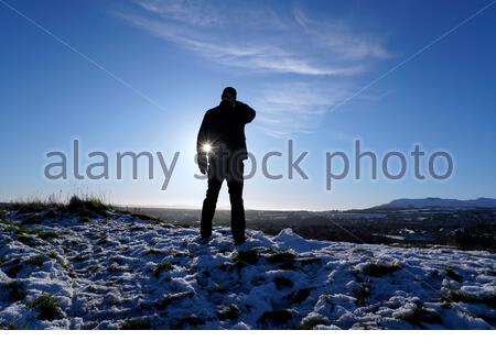 Édimbourg, Écosse, Royaume-Uni. 30 décembre 2020. Silhoueted contre le soleil d'hiver bas et prenant dans la vue d'Édimbourg et de collines de Pentland depuis les hauteurs d'Arthurs Seat et un Holyrood Park enneigé. Crédit : Craig Brown/Alay Live News Banque D'Images