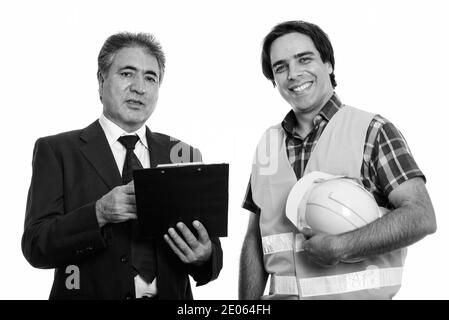 Persan senior businessman holding clipboard avec jeune homme persan construction worker smiling Banque D'Images