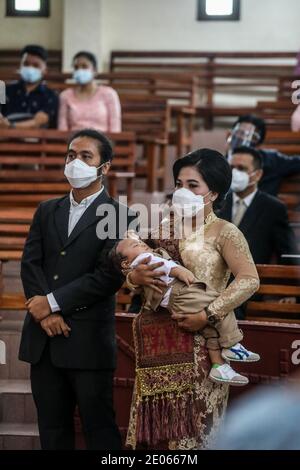 Medan, Sumatera du Nord, Indonésie. 26 décembre 2020. Une femme portant un masque facial est vue porter son enfant au prêtre pour la cérémonie de baptême à l'église protestante Batak Karo, à Medan. Crédit : Kartik Byma/SOPA Images/ZUMA Wire/Alay Live News Banque D'Images