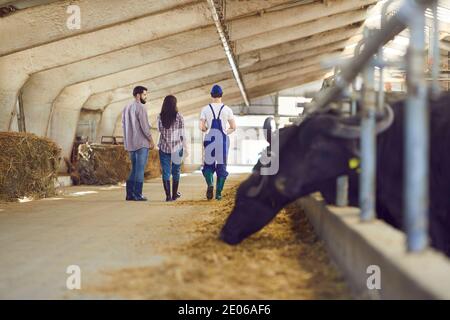 Les gens se réchauffent dans des bottes en uniforme et en caoutchouc qui marchent le long des étals avec des vaches et des taureaux Banque D'Images