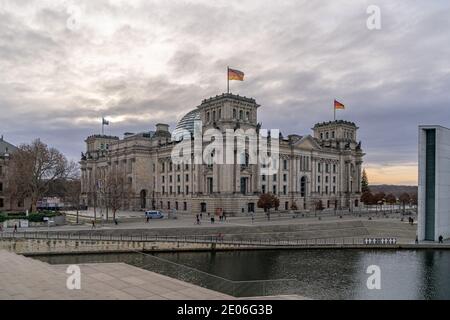 28 décembre 2020, Berlin, le bâtiment Reichstag par le maître de chantier Paul Wallot sur la Platz der Republik avec des drapeaux le jour avec ciel nuageux. Le Reichstag est le siège du Bundestag allemand avec la zone plénière. Vue latérale depuis le côté Spree. | utilisation dans le monde entier Banque D'Images