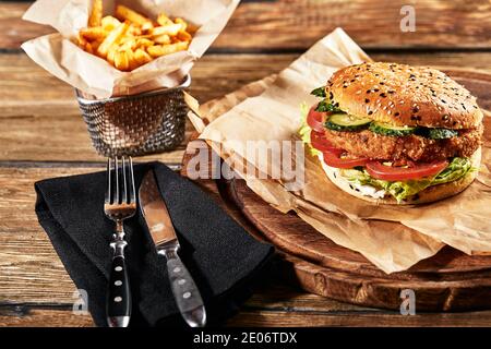 Le concept de restauration rapide américaine. Un hamburger américain juteux avec deux viandes de bœuf et une bière foncée sur fond de bois. Copier l'espace. Banque D'Images