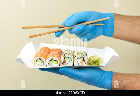 Concept de livraison de sushi, livraison par coursier d'un lot de sushi dans un contenant écologique en papier à la maison Banque D'Images