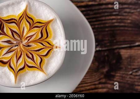Une délicieuse tasse de cappuccino chaud se trouve sur la table en bois. C'est un art sur le Latte Banque D'Images