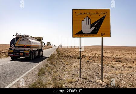 Anti-Atlas, Maroc. 25 février 2020.camion sur une route dans le désert. Panneau de route représentant une main de Fatma (Khamsa) pour se protéger contre l'œil méchant. Banque D'Images