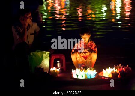 Fille vendant des lanternes en papier au festival de pleine lune à Hoi an, Vietnam avec des lumières reflétées dans la rivière Banque D'Images