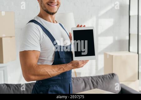 vue rognée d'un mouvement joyeux dans un uniforme tenant la tablette numérique avec écran vide dans l'appartement Banque D'Images