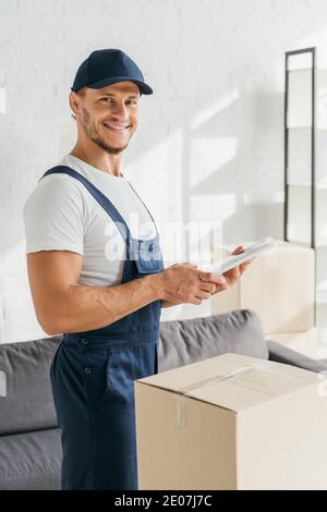 bonne motionnaire dans l'uniforme tenant la tablette numérique dans l'appartement Banque D'Images