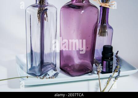 Plantes de lavande en bouteilles avec des huiles essentielles, sur fond blanc. Banque D'Images