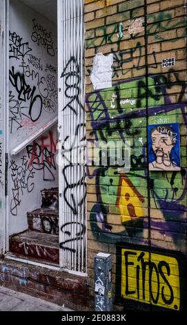 Porte d'entrée d'un appartement avec des marches menant à couvert de graffiti sur Brick Lane, Shoreditch, Tower Hamlets, East London. Banque D'Images