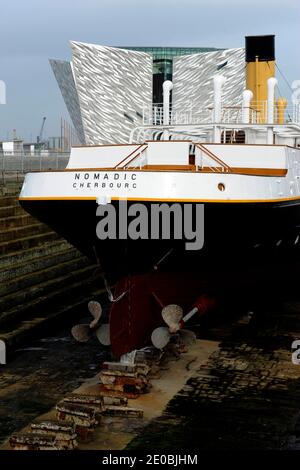 SS Nomadic, le dernier navire White Star Line restant est actuellement en cours de restauration à Hamilton Dock, en face du bâtiment Titanic Belfast, qui célèbre l'histoire du port de Belfast, à Belfast, au Royaume-Uni, en mars 2012. Le 10 avril 1912, le bateau a transporté 142 passagers de première et deuxième classe au Titanic depuis le port de Cherbourg. Conçue par Thomas Andrews, l'architecte du Titanic, elle a été construite à Harland & Wolff sous le profil géant du Titanic et de l'Olympic par les mêmes ouvriers. Après avoir servi olympique pendant des années , le bateau a atteint la Seine et est devenu une boîte de nuit ! Elle est retournée à Belfast en 2006 an Banque D'Images