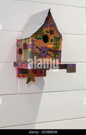 Gros plan d'un birdhouse d'art folklorique coloré sur carreaux de céramique blanche mur dans la salle de bains à l'intérieur de la maison contemporaine Banque D'Images