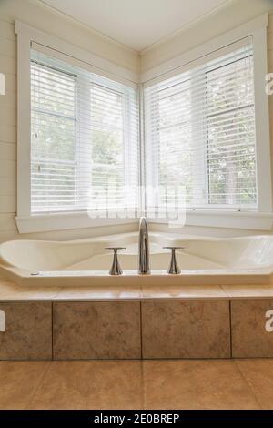 Baignoire jacuzzi surélevée enveloppée dans une base en céramique beige nuancé salle de bains à l'étage à l'intérieur de la maison contemporaine Banque D'Images