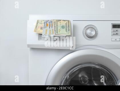 Billets de dollars dans le lave-linge sur fond blanc. Concept de lavage coûteux Banque D'Images