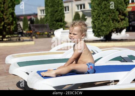 Un enfant se reposant sur un fauteuil inclinable à l'Aquapark en été Banque D'Images