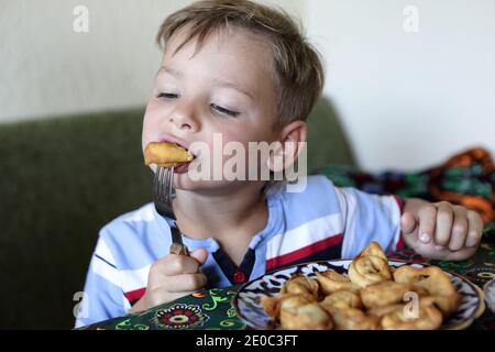 Un enfant mange des boulettes frites dans un restaurant Banque D'Images